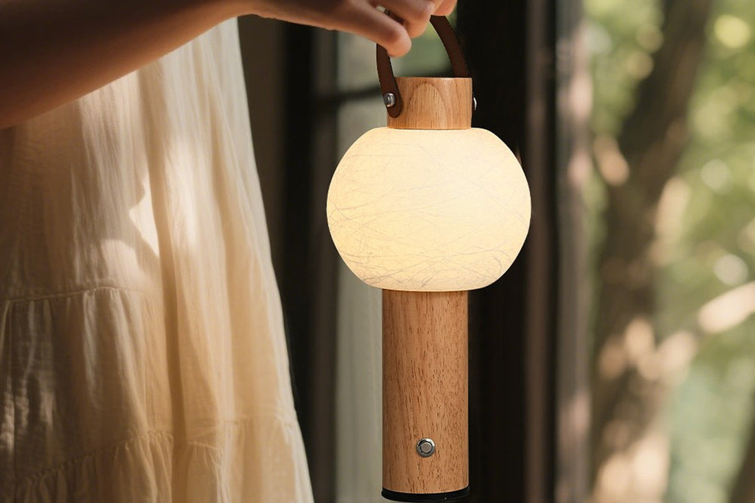 Hand carrying the lit compact ARDEN LUME table lamp by its handle in a warm corner.