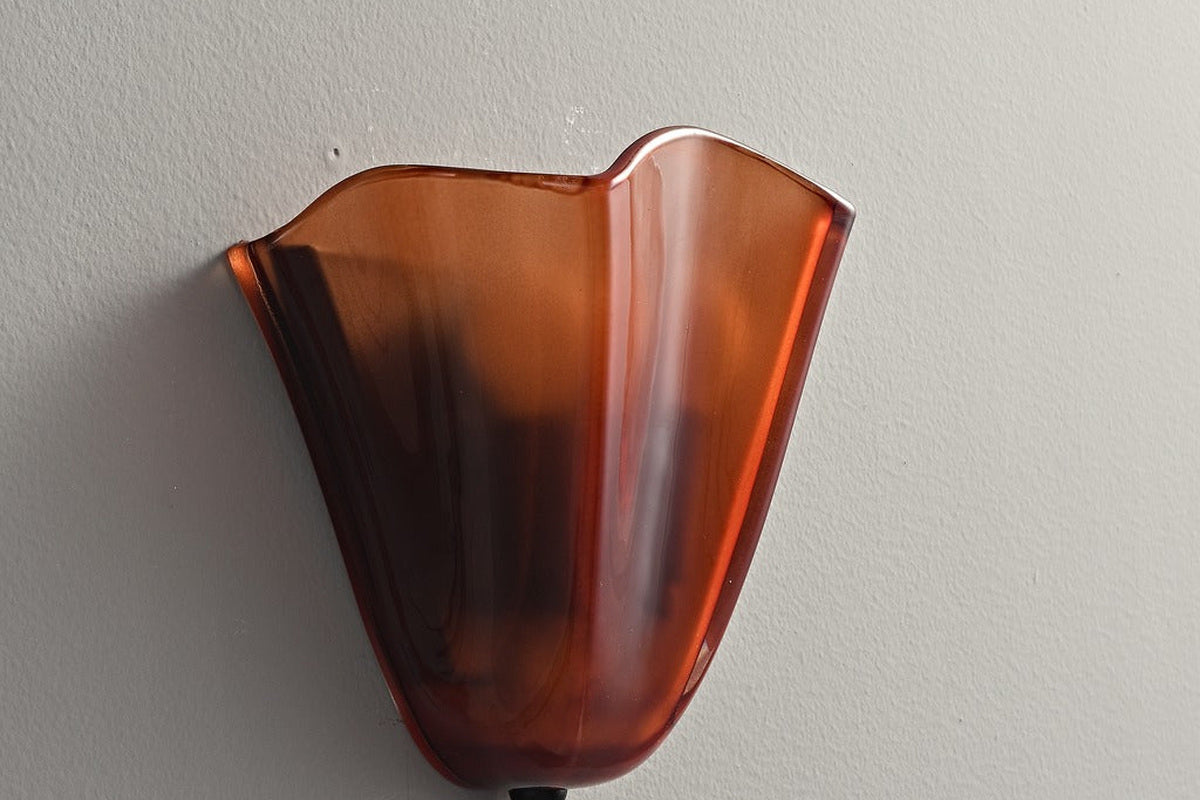 Real product photo of the Amber shell-petal glass wall sconce switched off against a pale wall.