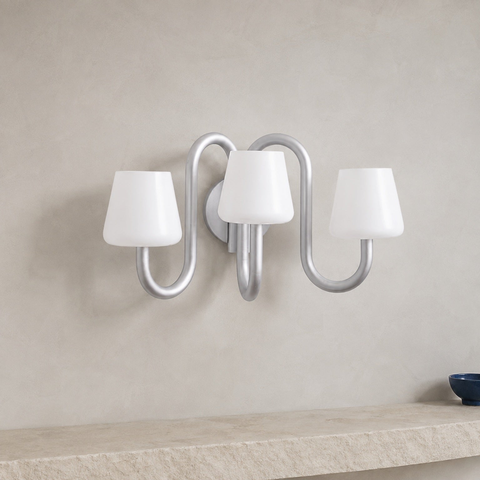 Apollo gray aluminum and opal glass three-light wall sconce mounted flush to a solid plaster wall