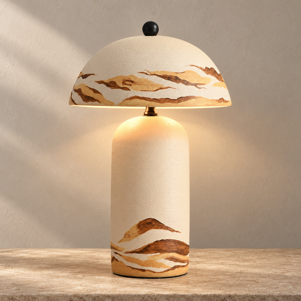 Teravelle Desert Ivory hand-painted ceramic table lamp glowing on a warm stone surface