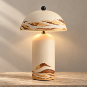 Teravelle Desert Ivory hand-painted ceramic table lamp glowing on a warm stone surface