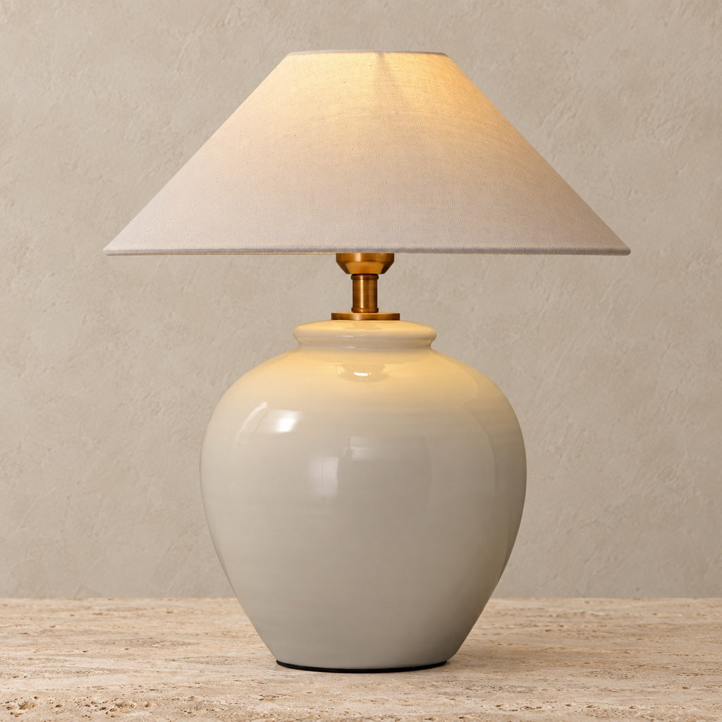 Monvelle large off-white gloss ceramic table lamp on a light greige travertine surface