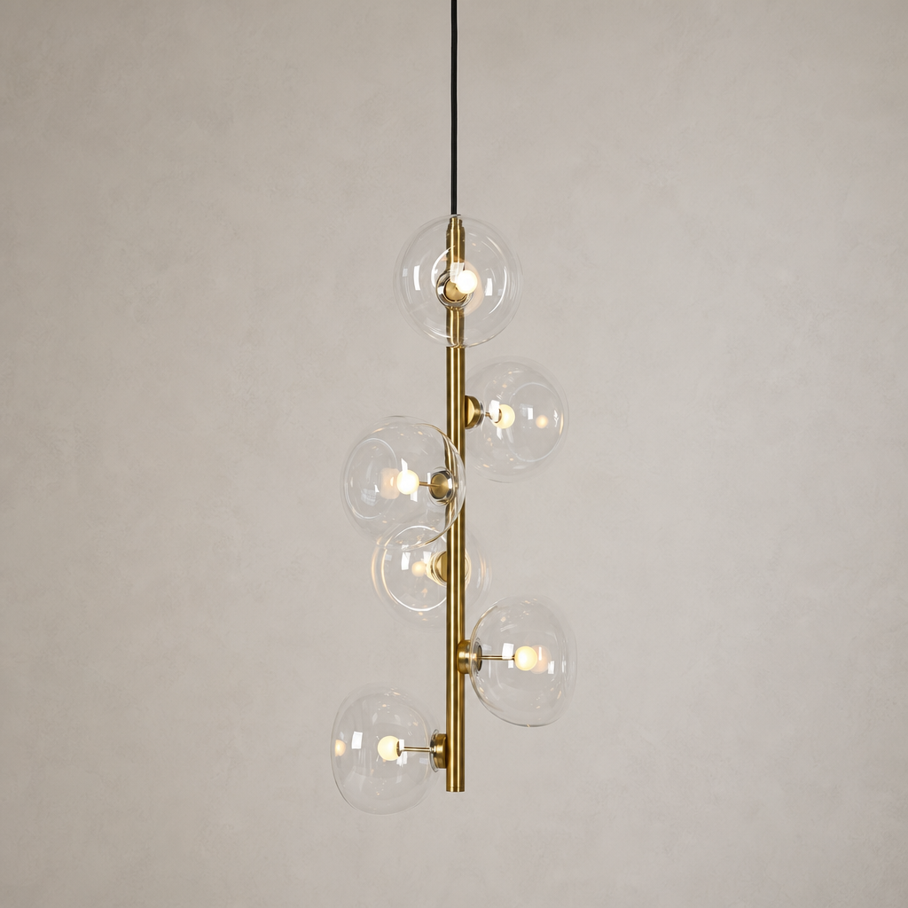 Clear glass six-light vertical pendant in Natural Brass on a warm neutral background