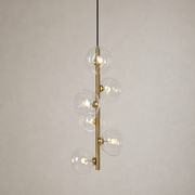 Clear glass six-light vertical pendant in Natural Brass on a warm neutral background