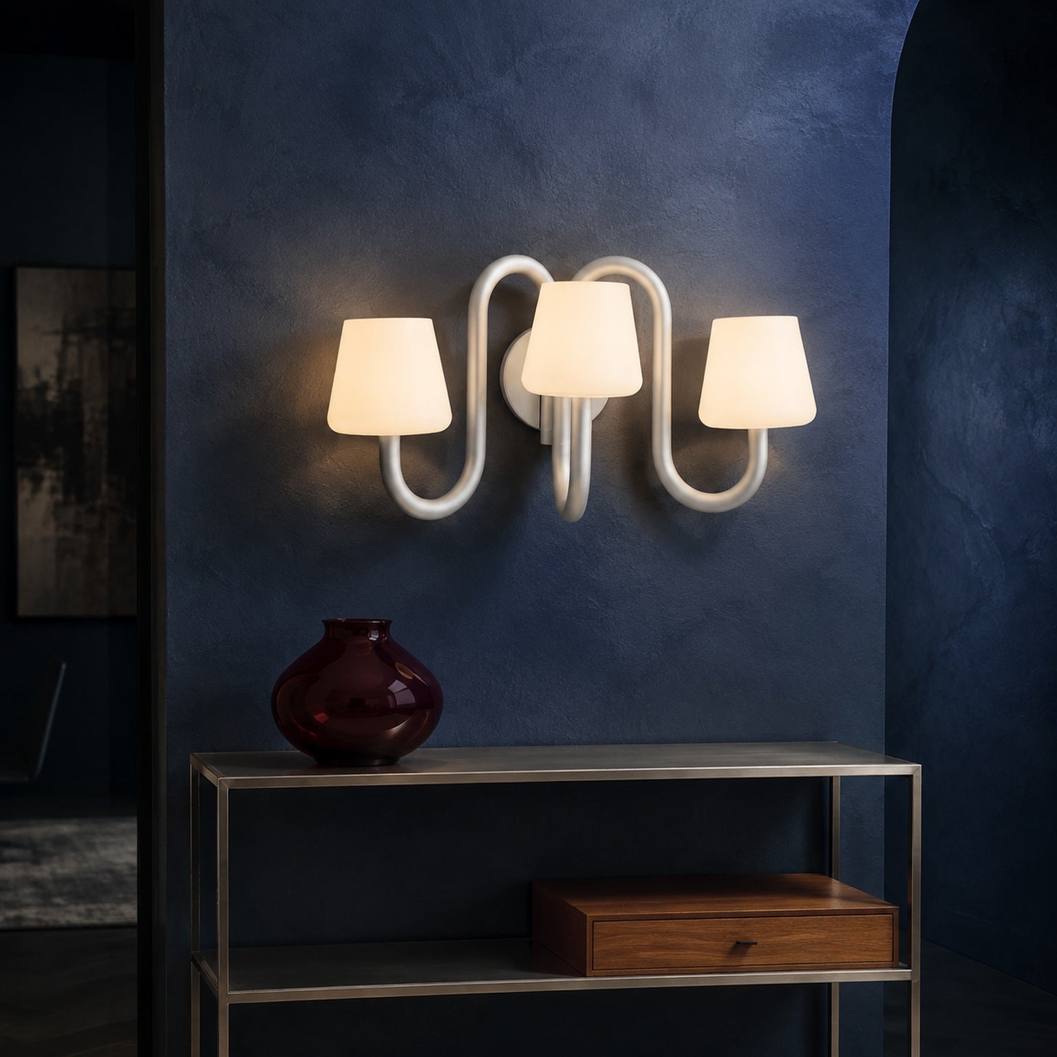 Apollo three-light wall sconce installed on a cobalt wall above a brushed metal console