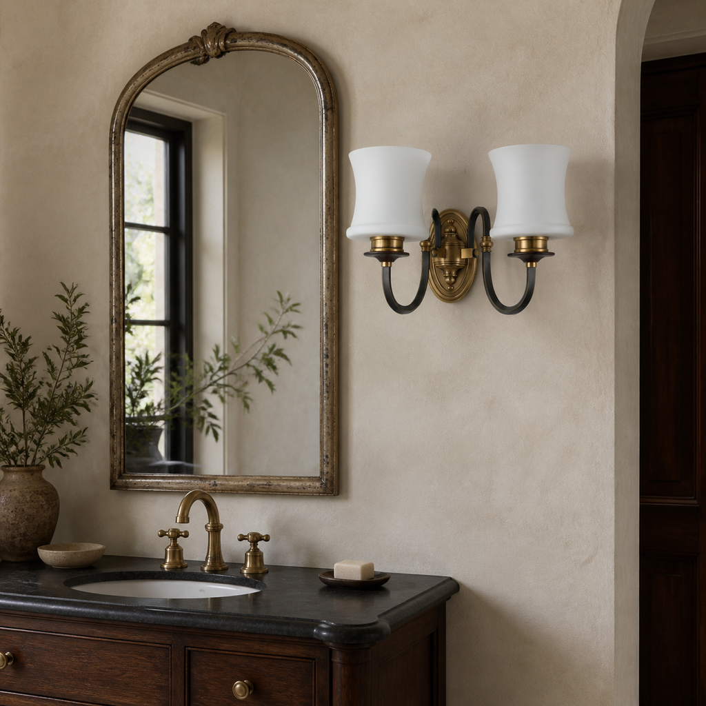 Unlit Ebonelle two-light wall sconce placed off-center beside an antiqued mirror with wall plate flush to plaster
