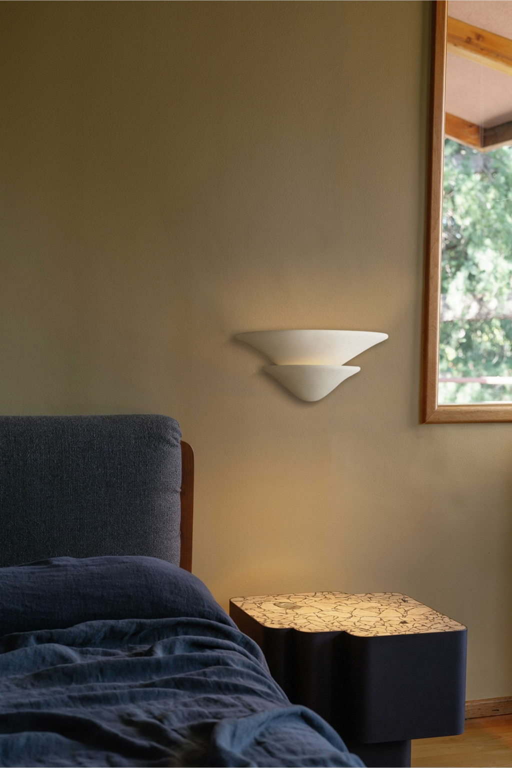 Sculptural Double-Tier Plaster Wall Sconce — complete real wall sconce beside a bed