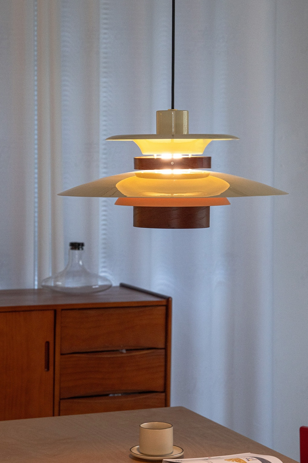 Layered Aluminum and Walnut Pendant Light — complete illuminated pendant in a real dining interior
