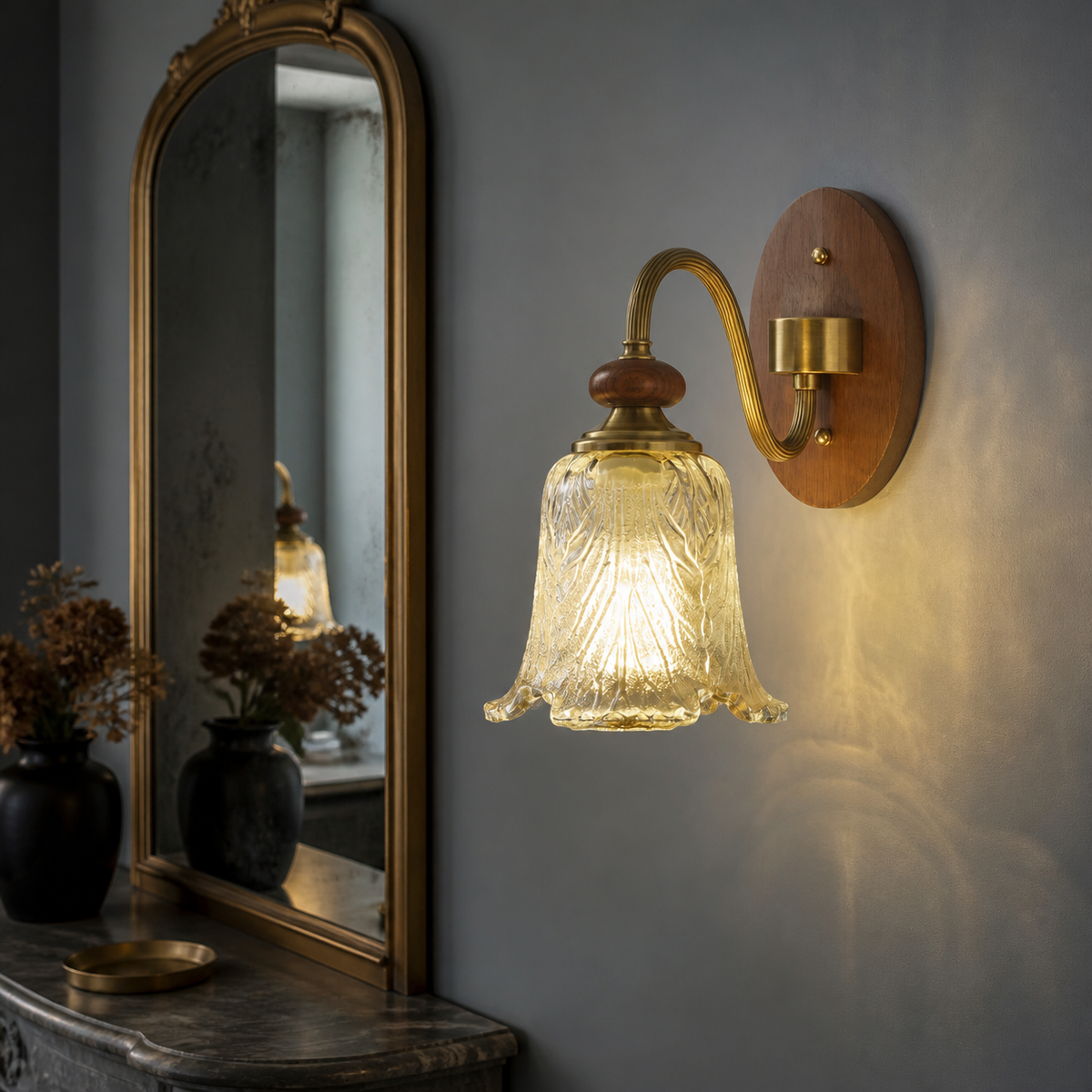 Sculpted leaf glass wall sconce on the right beside a dry smoky-blue dressing table