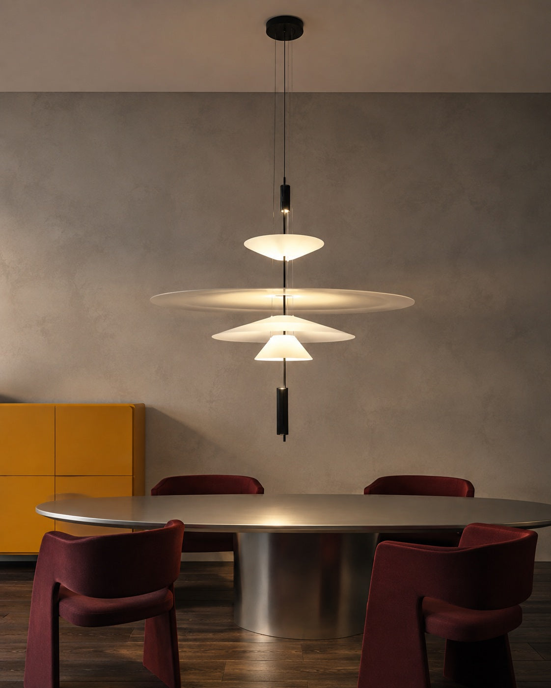 Four-tier layered acrylic disc pendant above a modern metal dining table