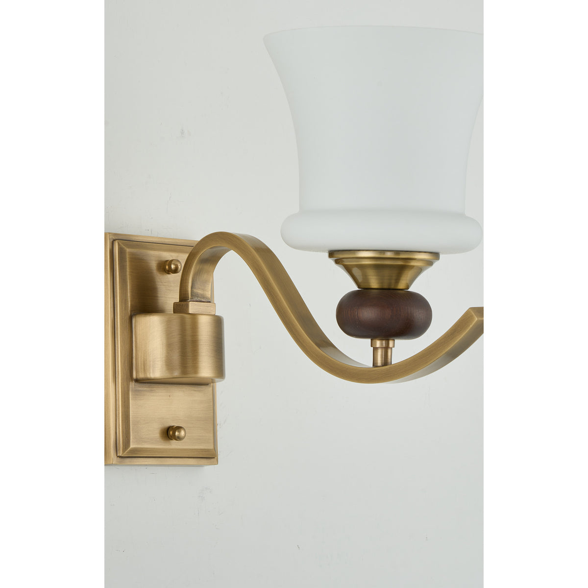 Supplier real detail crop of the Brontelle curved brass arm and dark ash-wood collar