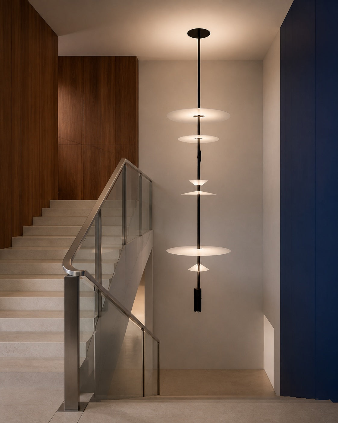 Six-tier layered acrylic disc pendant installed in an open stair void away from circulation paths