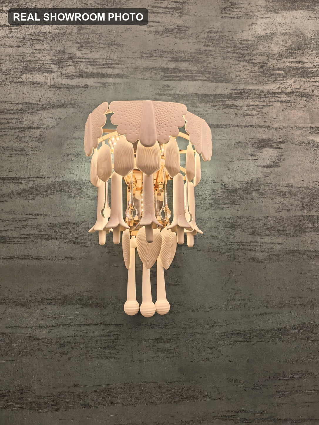 Real showroom photo — Muguetelle ivory ceramic wall sconce illuminated view