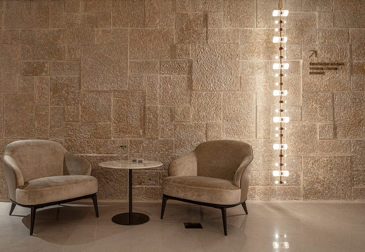 Royal vertical pendant installed in a furnished stone-wall lounge
