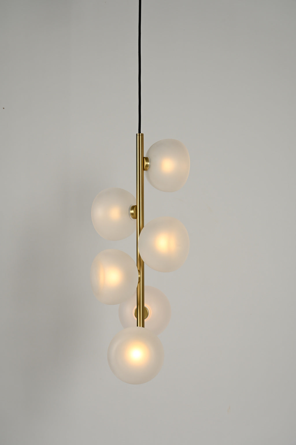 Frosted glass six-light vertical pendant in Natural Brass, illuminated product view