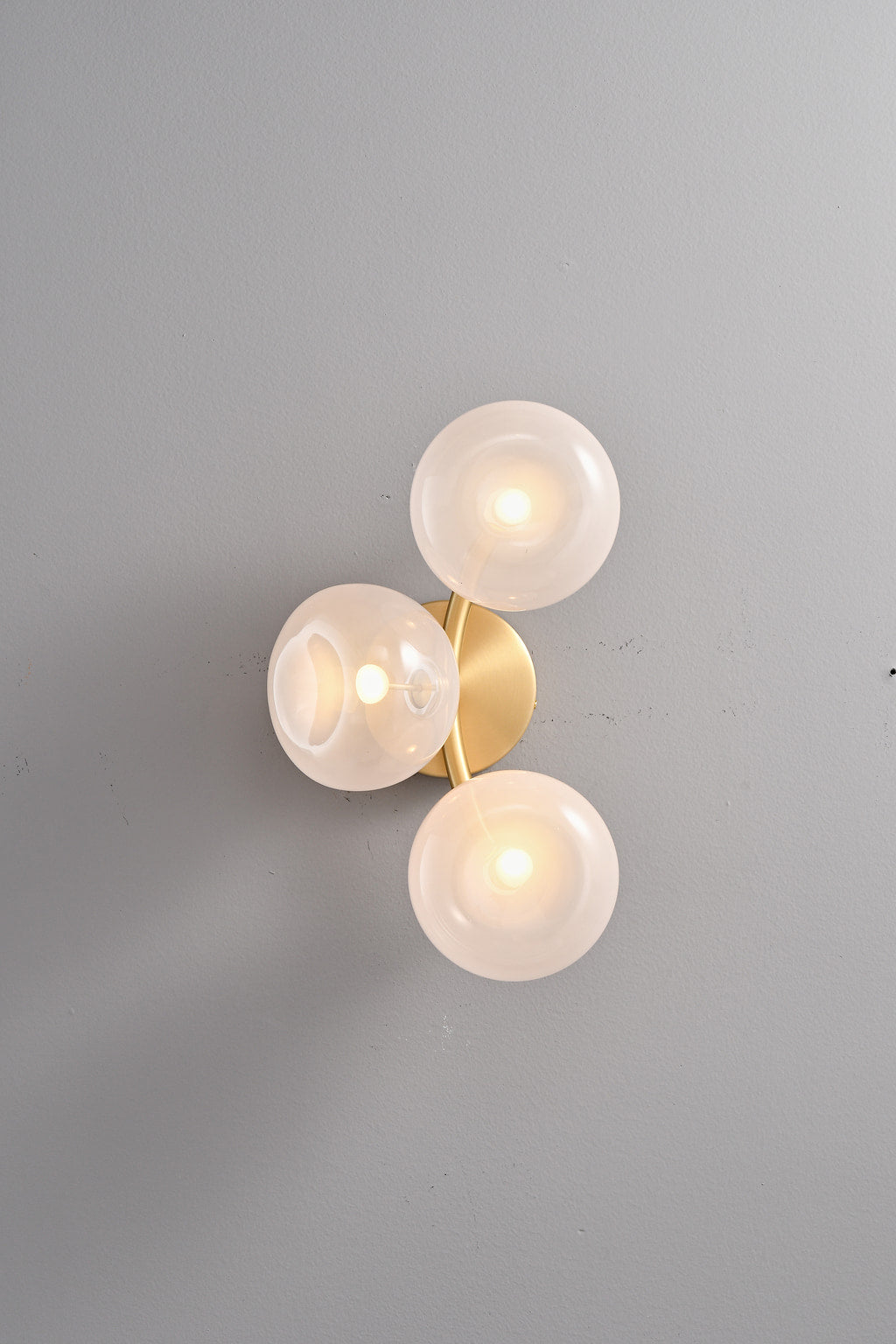 Modern Glass Globe Branch Wall Sconce in Natural Brass - 3 shades pink glass, lights on front view