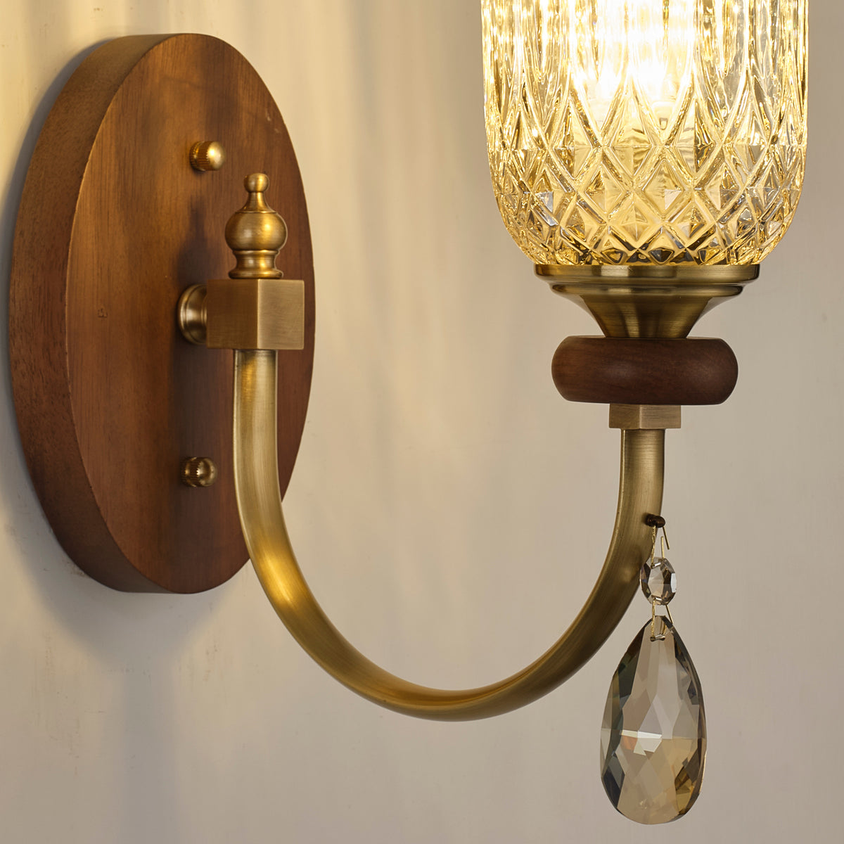 Supplier real wall sconce detail showing the antique brass-toned arm and crystal drop