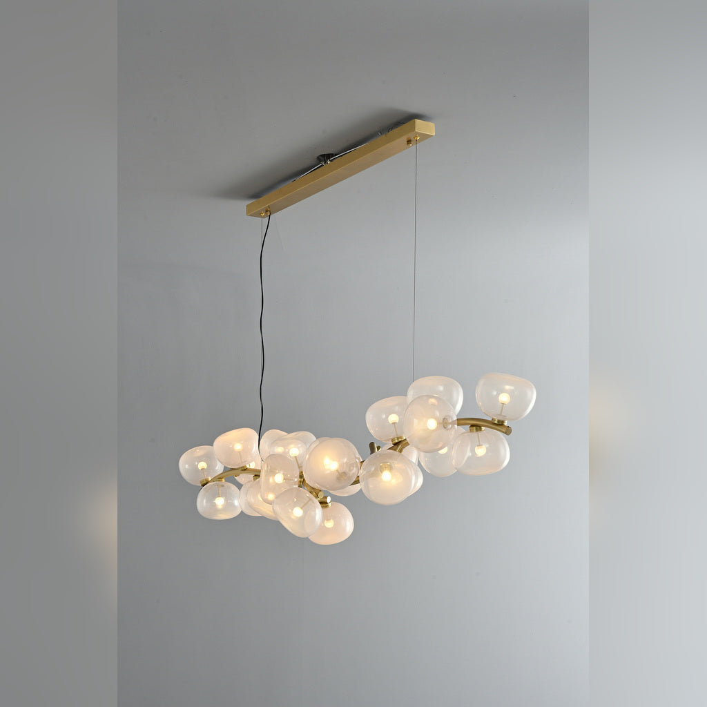 Clear glass 26-light linear chandelier in Natural Brass, illuminated three-quarter product view