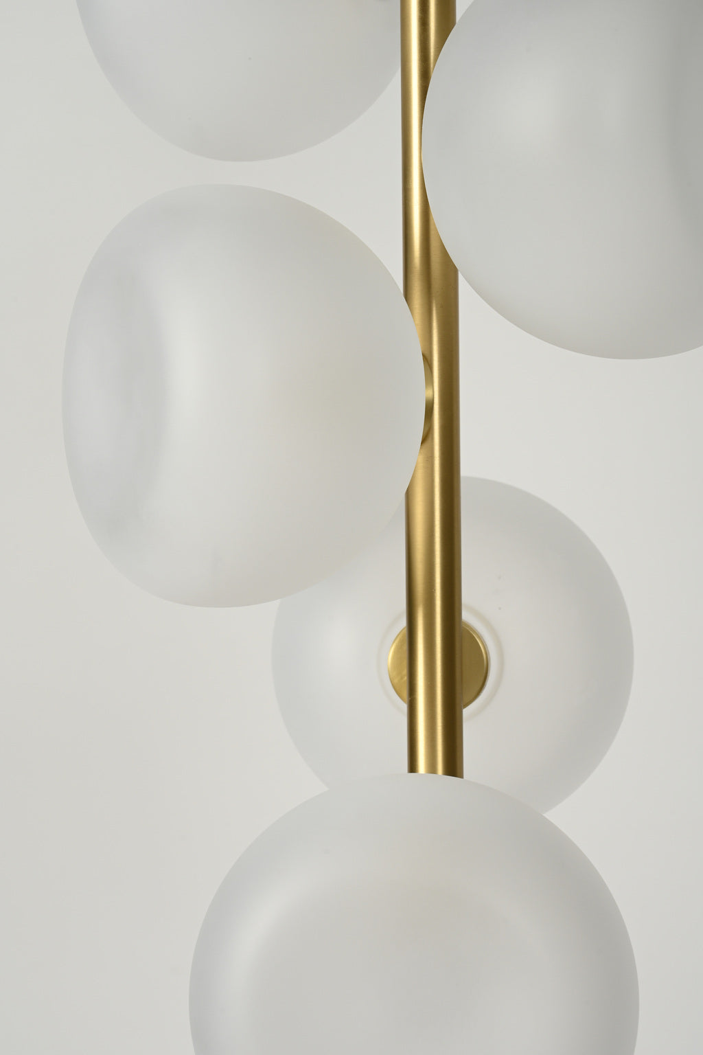 Frosted glass globes and Natural Brass vertical stem detail on the six-light pendant