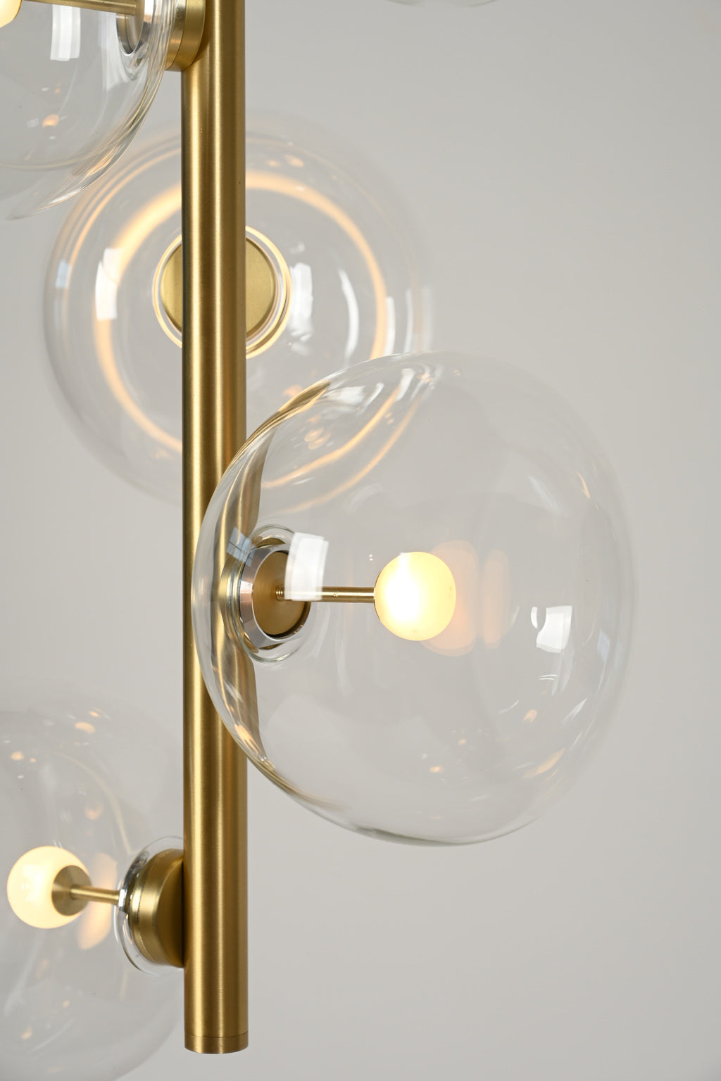 Clear glass globe connection and Natural Brass stem detail on the six-light pendant