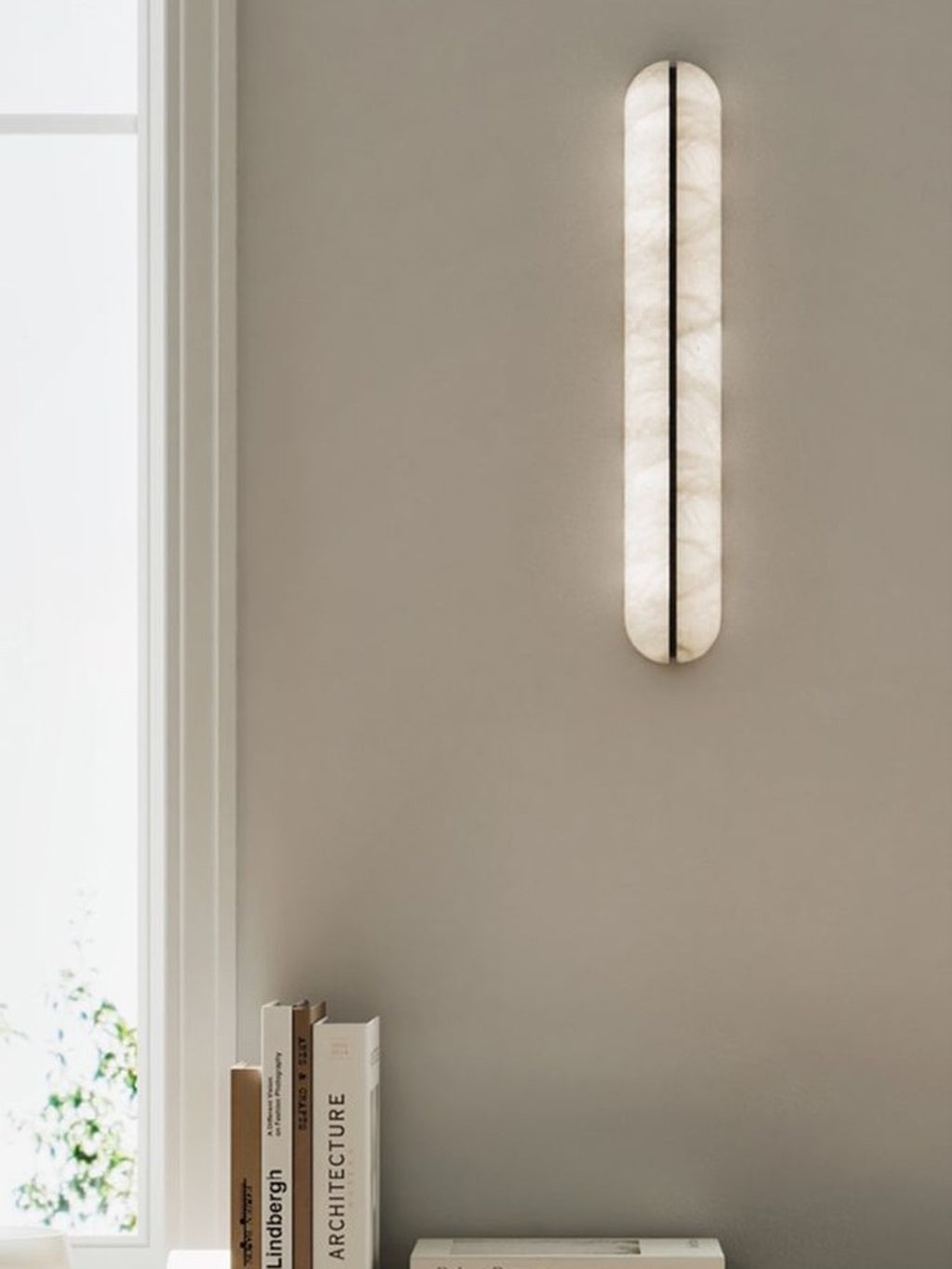 Slim alabaster capsule wall sconce switched off by an entryway window