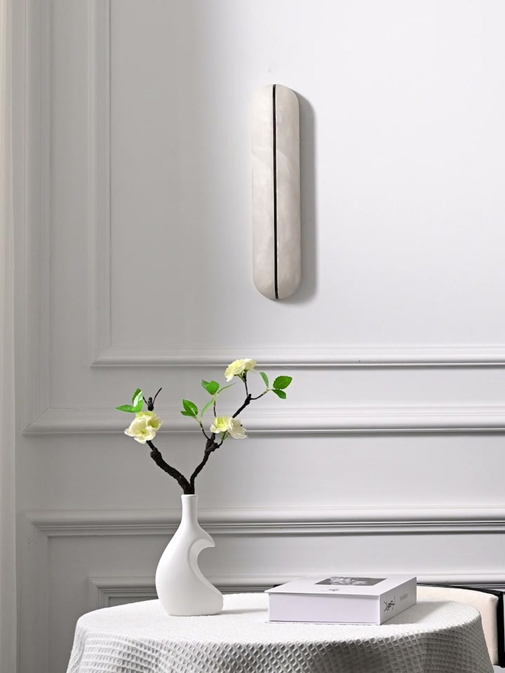 Slim alabaster capsule wall sconce switched off in a bright interior