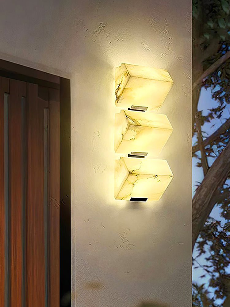 Three Modern Alabaster Geometric Wall Sconces illuminated beside a doorway