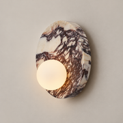 Lucie Round Marble Wall Sconce on a warm greige background; 25 cm white-purple marble disc; lower offset globe on