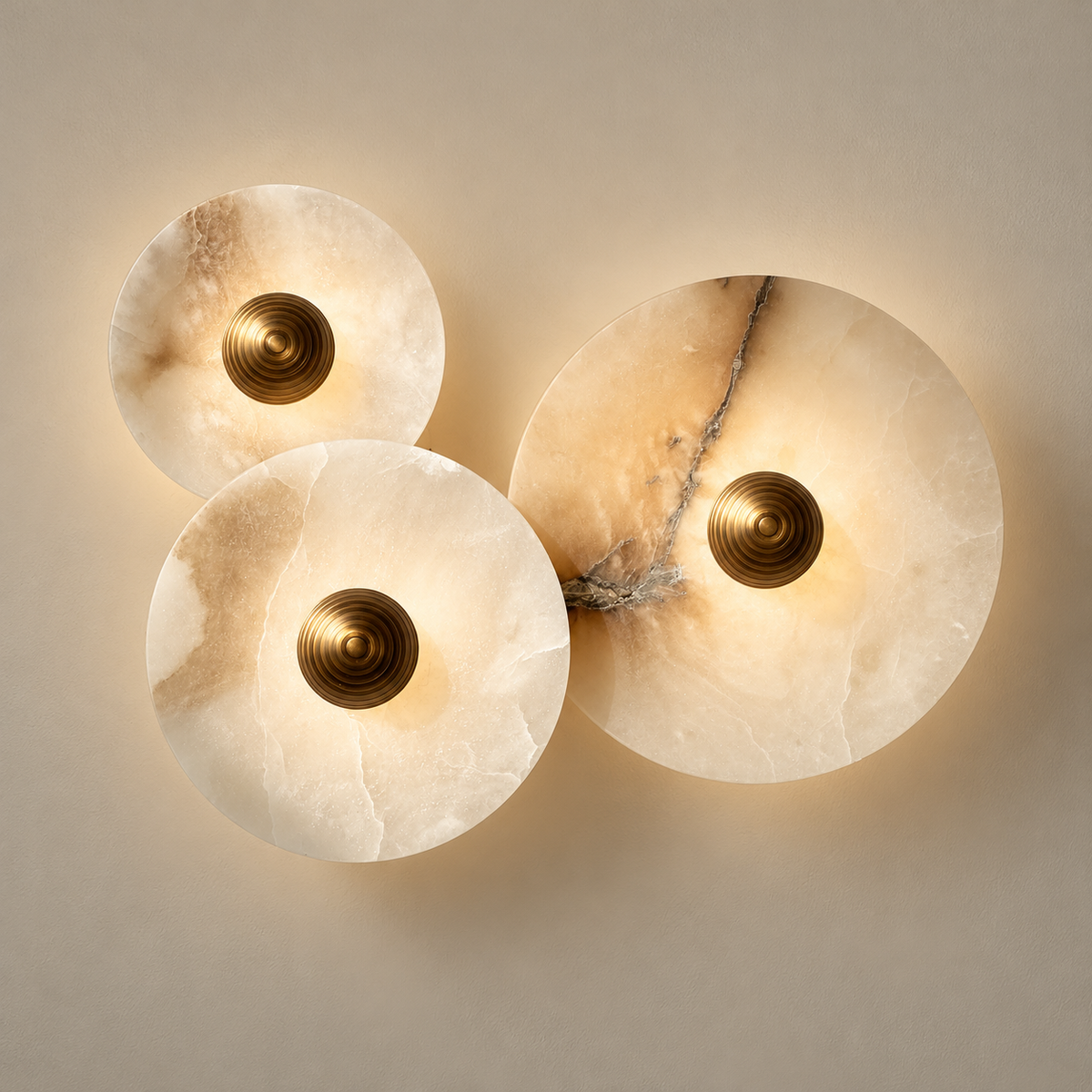 Marble and Alabaster Organic Modern Wall Sconce on a warm greige background; Three white alabaster overlapping discs; gold centre caps