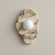 Organic Modern Textured Marble Wall Sconce on a warm greige background; White Marble A asymmetric organic shield plate; white opal globe