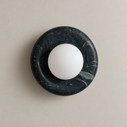 Orli Dark Green Marble Globe Wall Sconce on a warm greige background; Dark forest green marble circular plate; white opal globe