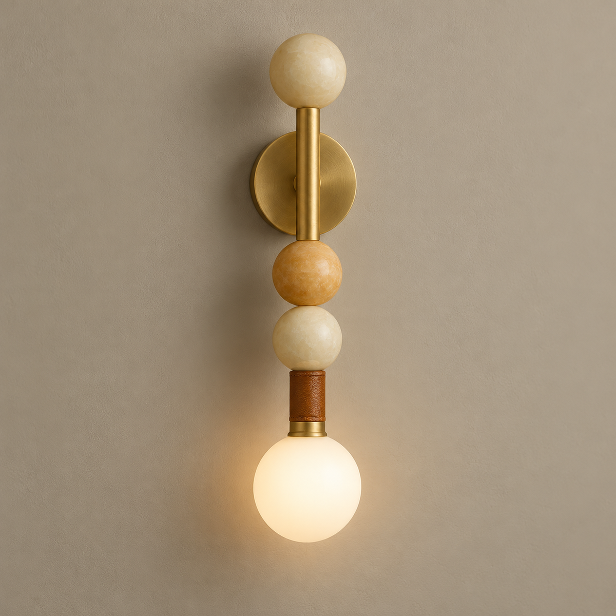 Sedona Art Deco Marble Wall Sconce on a warm greige background; Brass vertical rod; three warm ivory stone beads; bottom white opal bulb