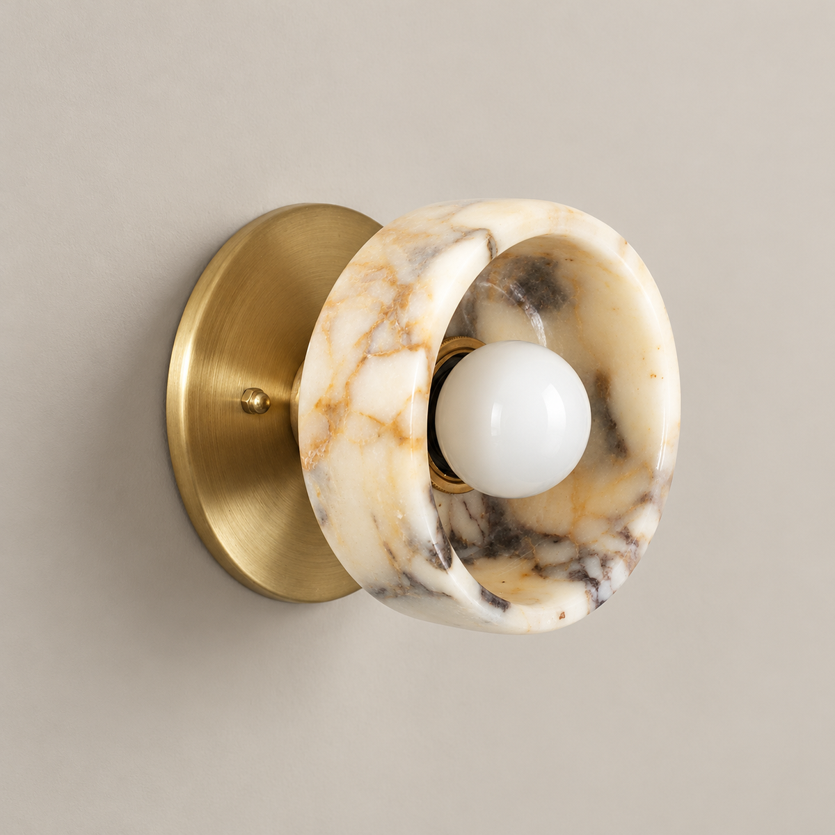 Piedra Marble Wall Sconce with Brass Body on a warm greige background; Piedra beige grey mineral concave marble cup with brass backplate