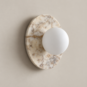 Leora Organic Modern Stone Wall Sconce on a warm greige background; Leora white marble and white glass globe