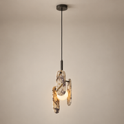 Megalith Marble Globe Pendant Light on a warm greige background; Megalith three stone paddles single hanging-wire pendant