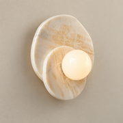 Astr Layered Stone Globe Wall Sconce on a warm greige background; Beige straight onyx, warm globe on