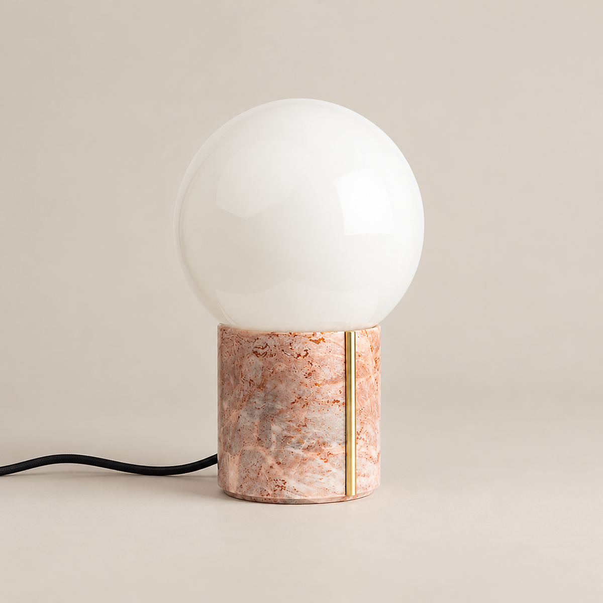 Nocte Marble Table Lamp with Glass Shade on a warm greige background; Pink marble base with brass inlay, off