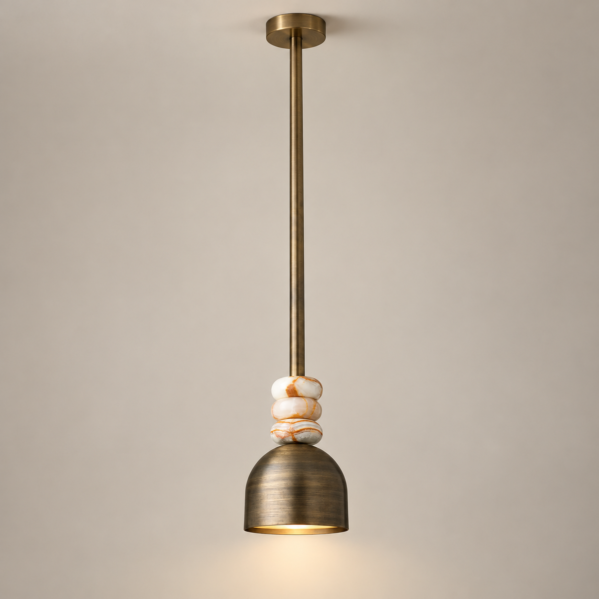 Boston Marble Pendant Light on a warm greige background; Weathered brass, white striped stone beads, long brass rod