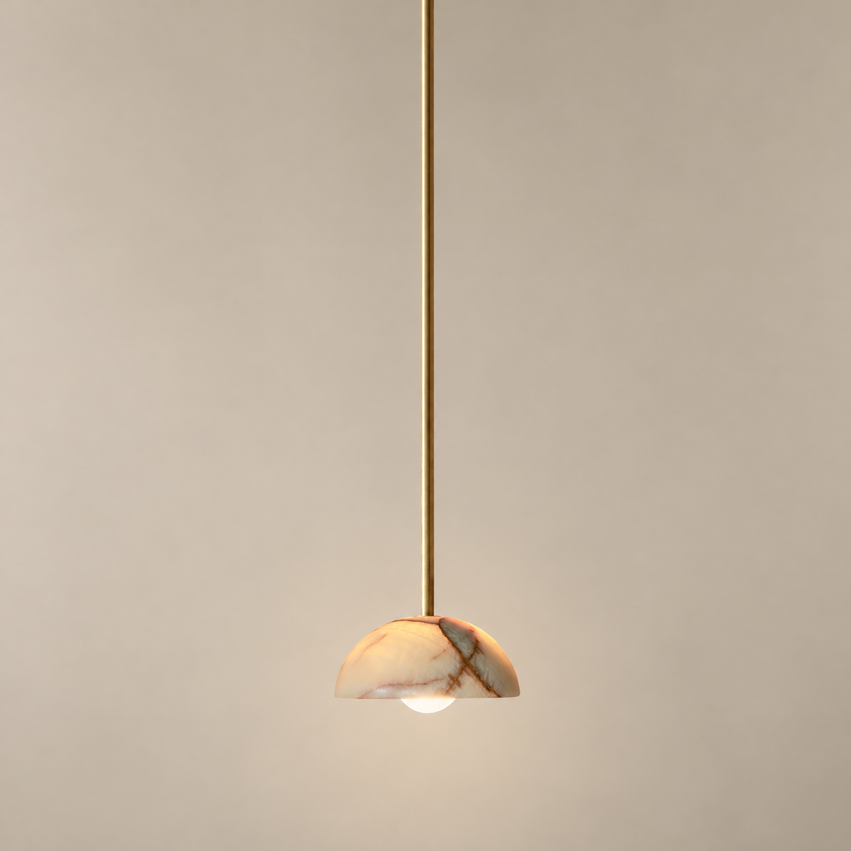 Aurelia Onyx Pendant Light on a warm greige background; Cyan onyx hemispherical shade, long solid brass rod