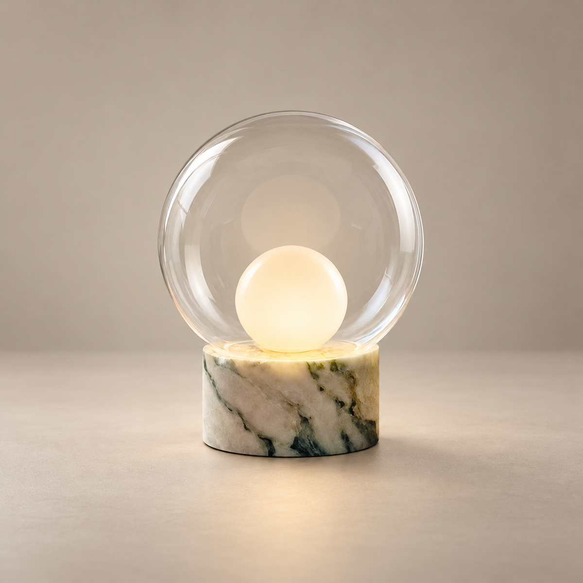 Boule Marble Table Lamp with Glass Shade on a warm greige background; White green veined marble base, clear glass globe