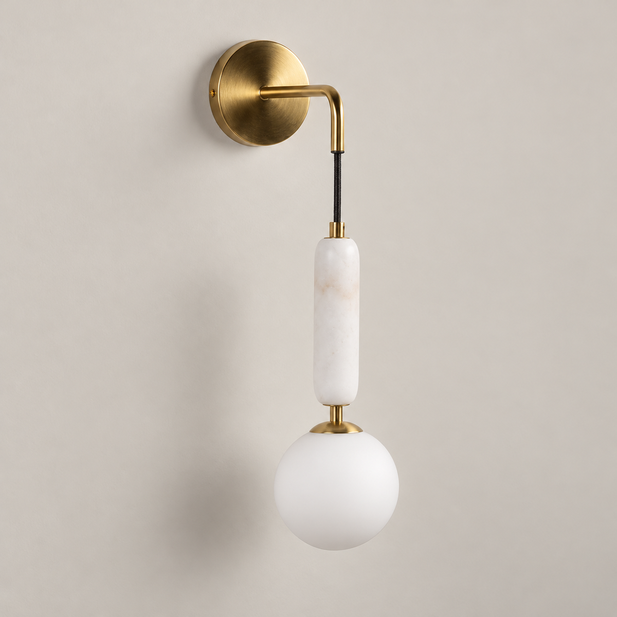 Valenes Marble Wall Sconce on a warm greige background; White marble capsule, brass curved arm, glass globe