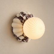 Verdessa Marble Globe Wall Sconce on a warm greige background; Purple white scalloped marble, spiral fluted glass globe