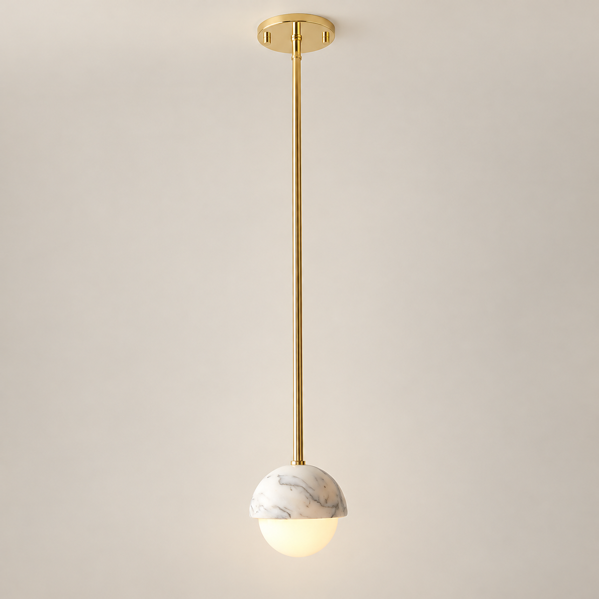Polaris Mid-Century White Marble Pendant Light on a warm greige background; Polished brass long suspension rod, white marble half globe