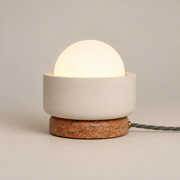 Pearla Ceramic Table Lamp with Marble Base on a warm greige background; Beige ceramic bowl, red brown stone foot and opal globe