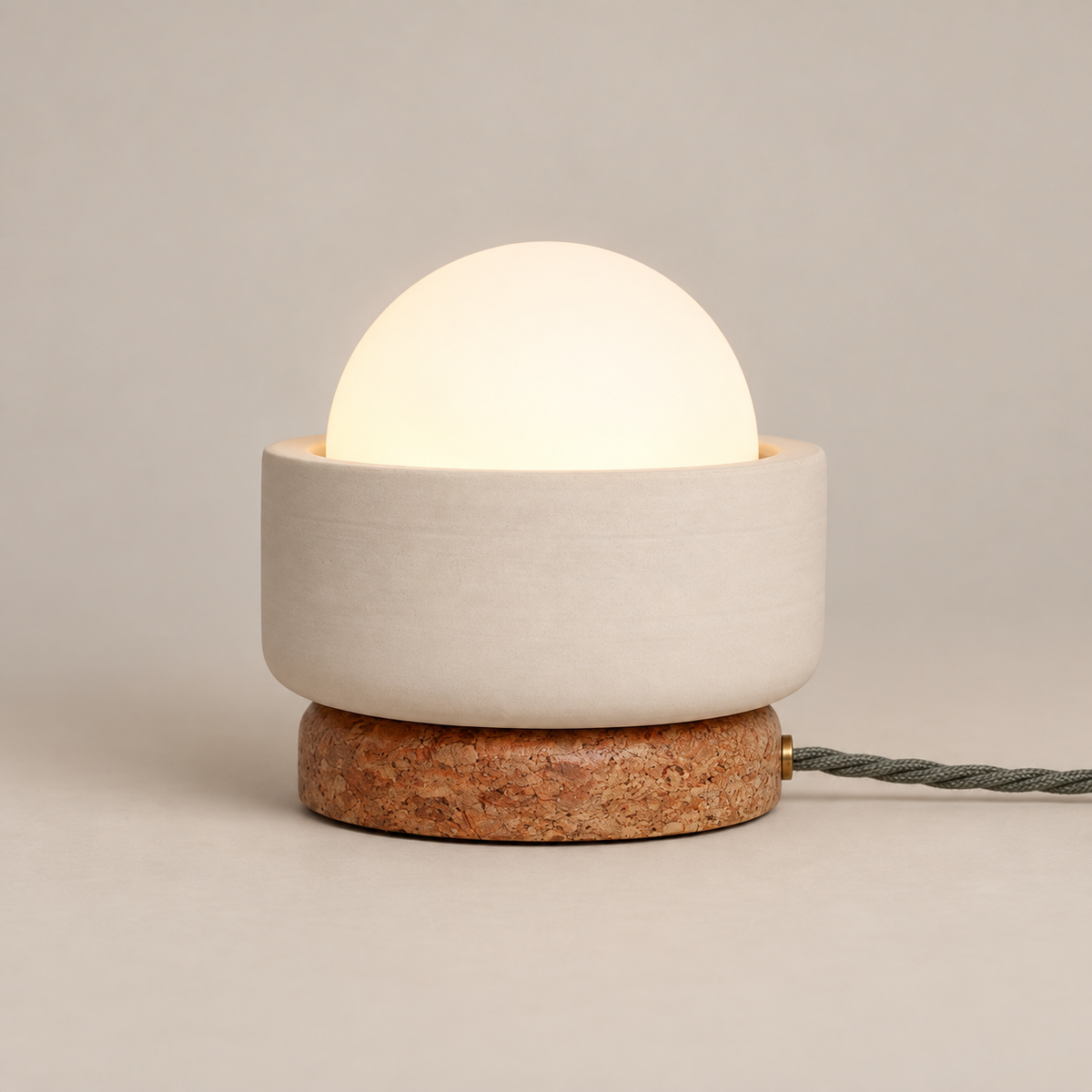 Pearla Ceramic Table Lamp with Marble Base on a warm greige background; Beige ceramic bowl, red brown stone foot and opal globe