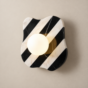 Zebra Minimalist Marble Wall Sconce on a warm greige background; Zebra marble wall sconce with warm glass globe