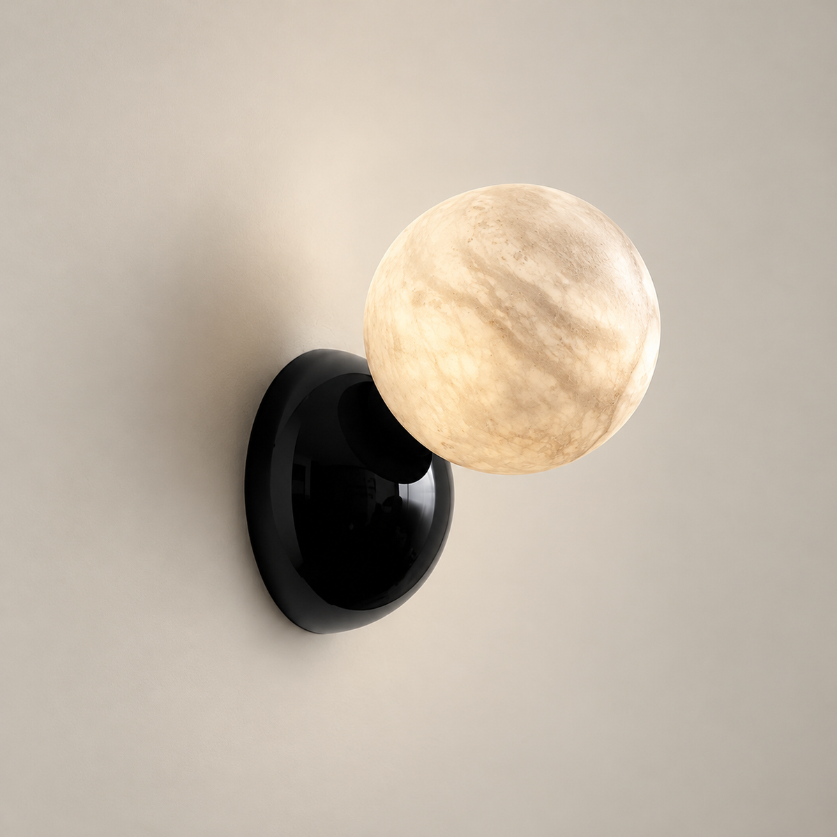 Callisto Eclipse Marble Wall Sconce on a warm greige background; Black mount and white alabaster adjustable globe wall sconce