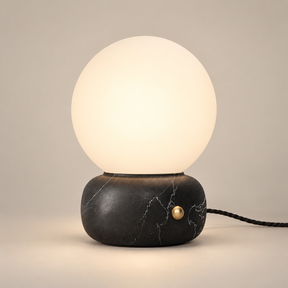 Naga Marble Table Lamp with Glass Shade on a warm greige background; Black marble rounded base globe table lamp