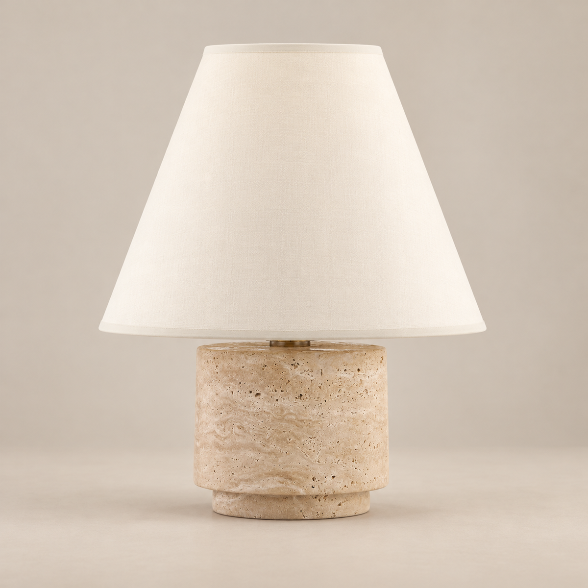 Bronte Travertine Table Lamp on a warm greige background; Bronte beige stone base / cream cone fabric shade
