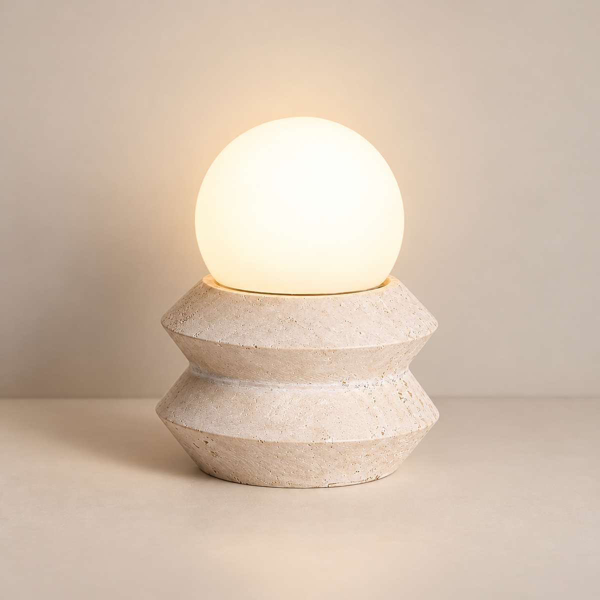 Fin Travertine Rechargeable Table Lamp on a warm greige background; Beige stone and white globe